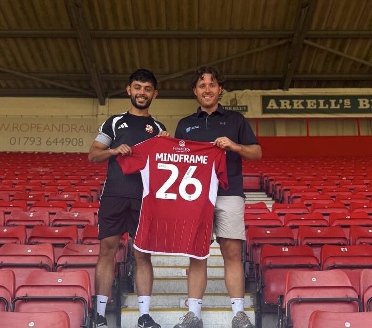 Jake Brown of Mindframe Performance and Adam Labelle, Swindon Town Head of Academy Player Care, holding a Mindframe shirt as Swindon Town's official sport psychology partner