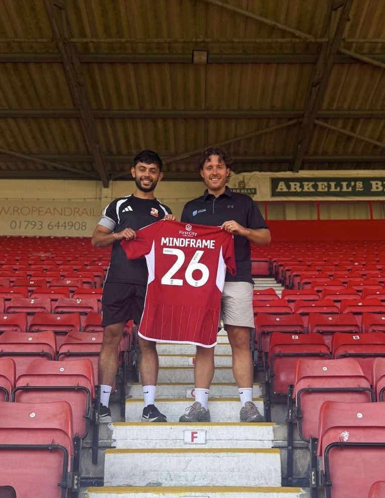 Jake Brown of Mindframe Performance and Adam Labelle, Swindon Town Head of Academy Player Care, holding a Mindframe shirt as Swindon Town's official sport psychology partner